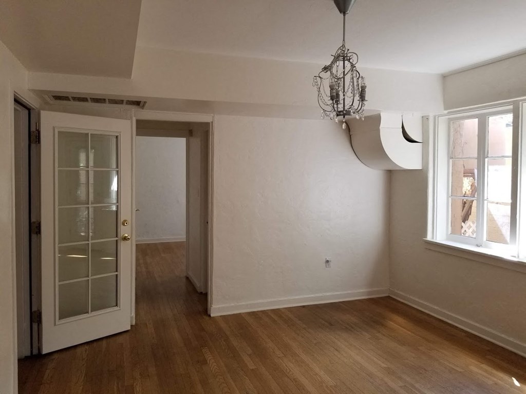 an empty room with a door and a chandelier