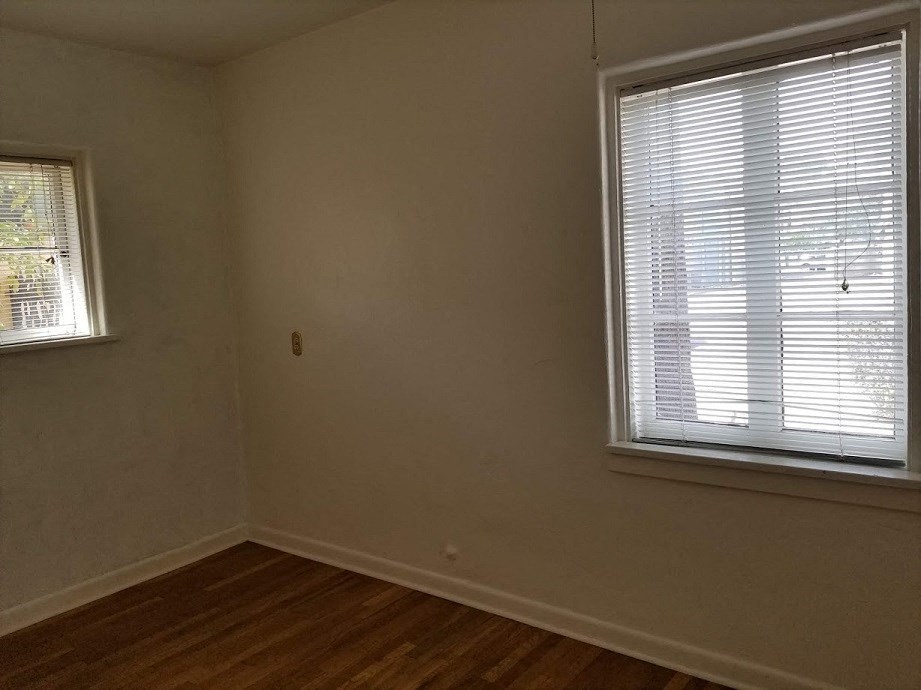 an empty room with a window and a wooden floor