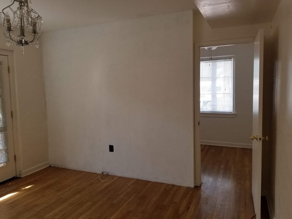 an empty living room with white walls and a wooden floor
