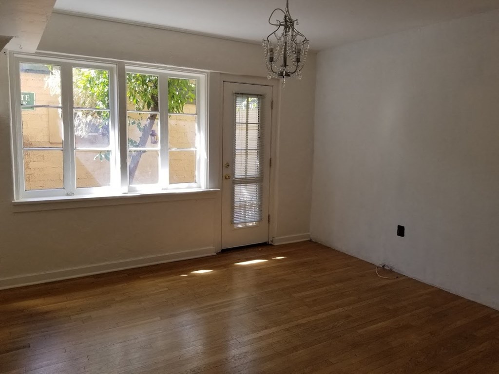 an empty living room with a wood floor and a window