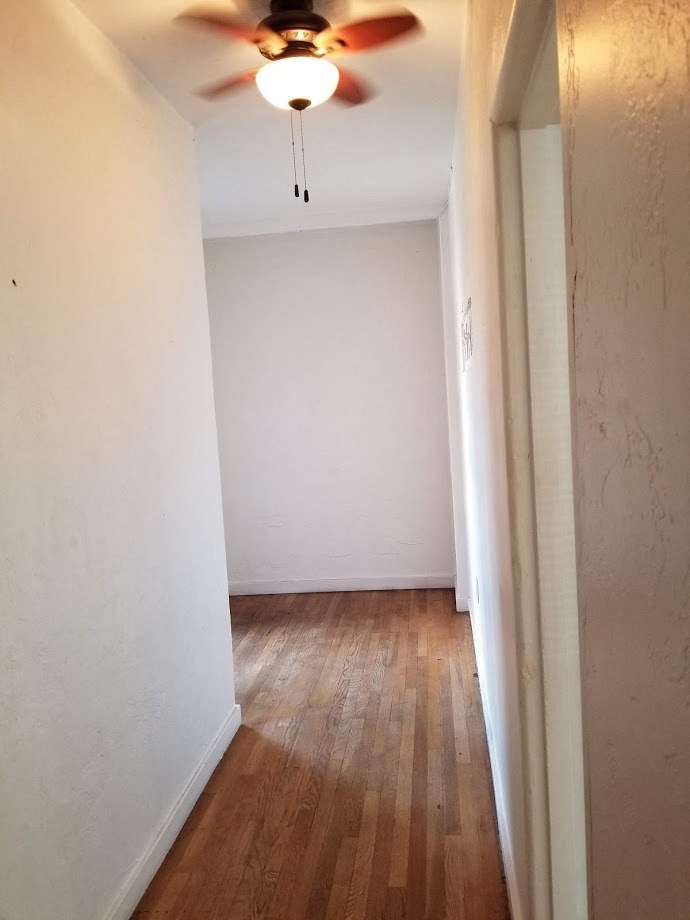 a room with a ceiling fan and a wood floor