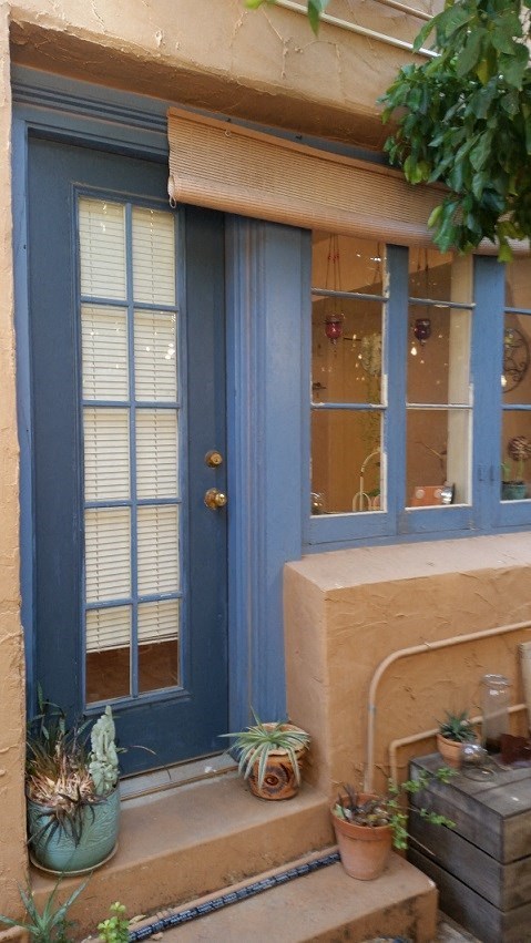 a porch with blue doors and potted plants