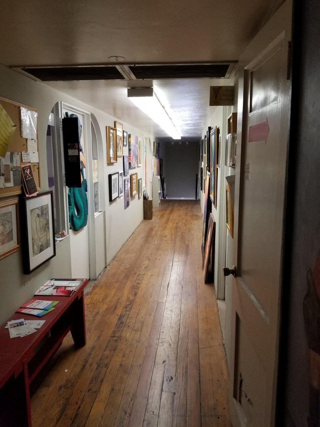 a gallery with paintings on the wall and a wooden floor