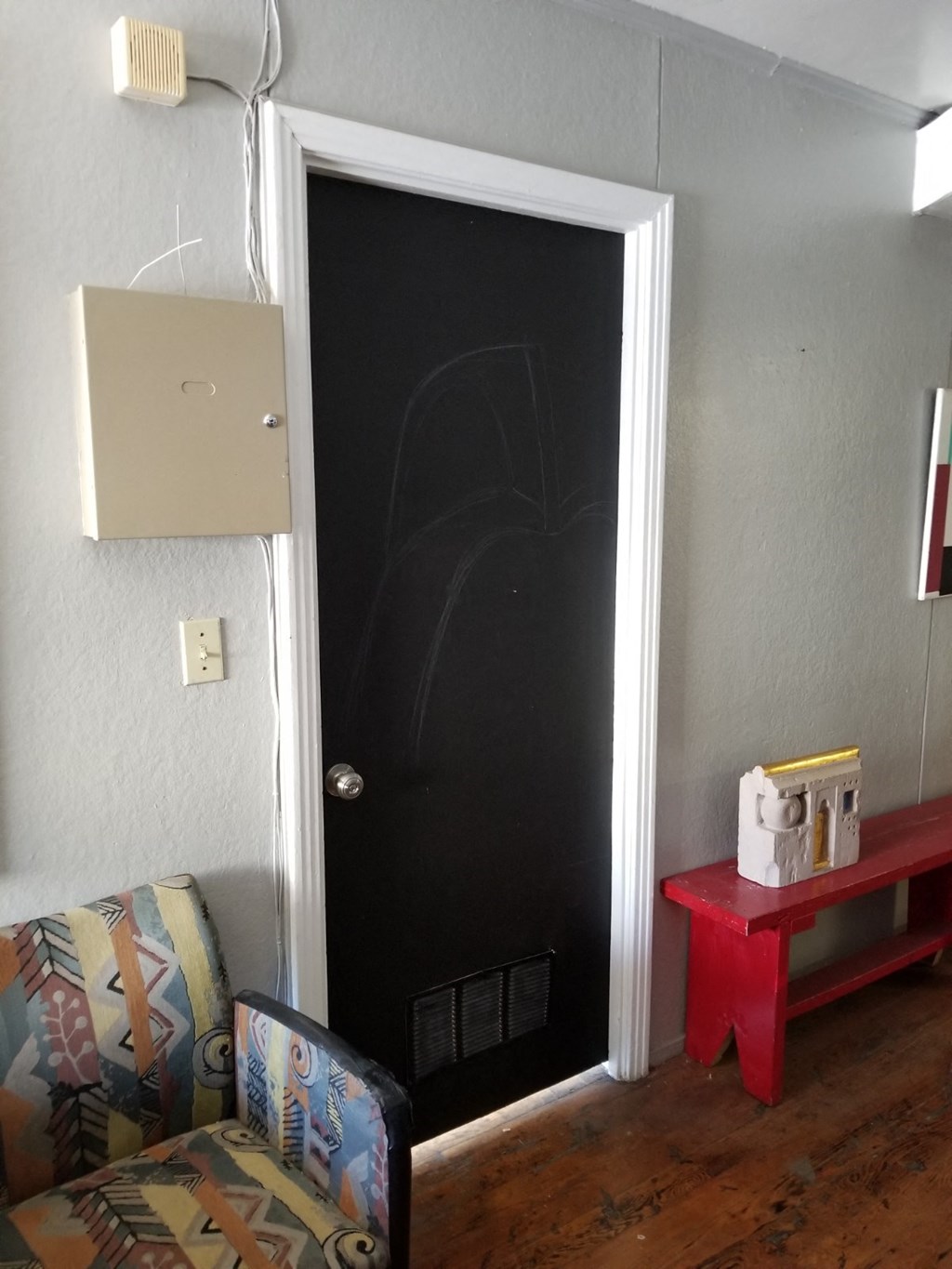 a room with a black door and a chair and a red table