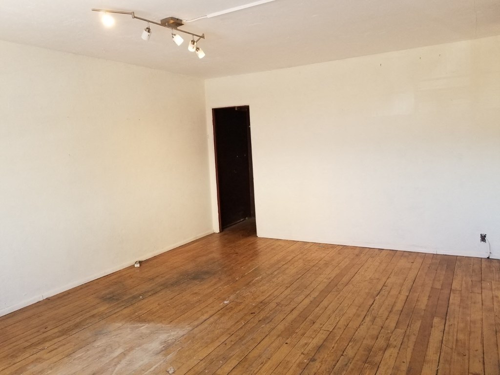 an empty room with a wooden floor and a black door