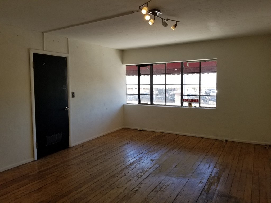 an empty living room with a window and wooden floors