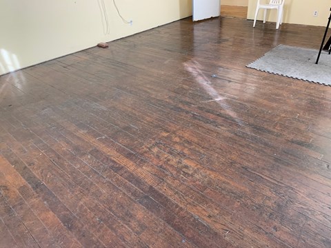 a wooden floor in a room with a rug and a chair
