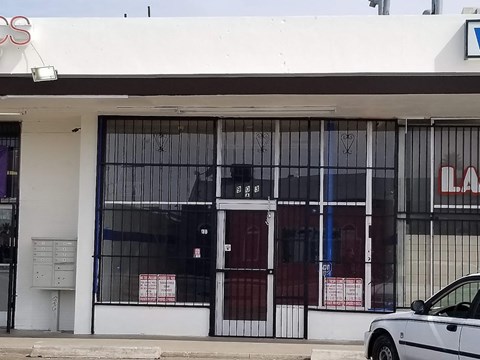 a white car parked in front of a building with glass doors