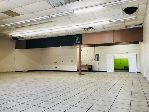 a large room with a white tiled floor and a green door