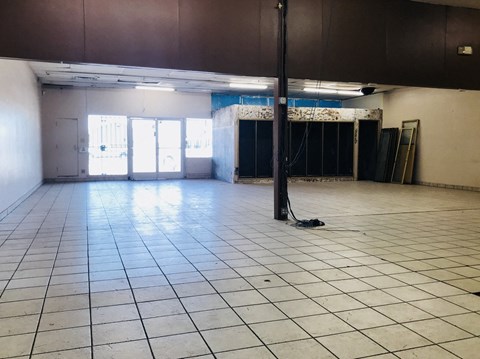 a large empty room with a tile floor and a pole