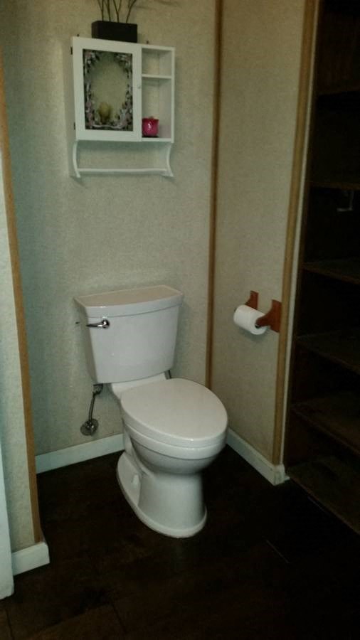 a bathroom with a toilet and a shelf on the wall