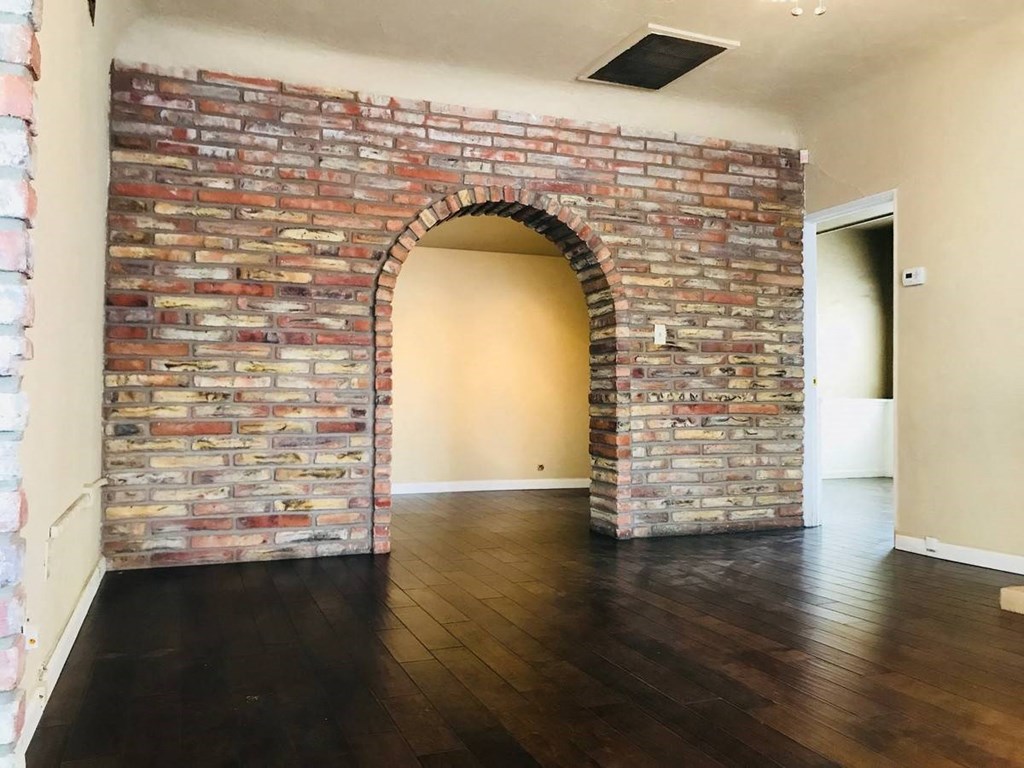 an exposed brick wall in a living room with wood floors