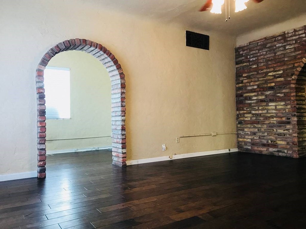 an empty room with a brick wall and wooden floors
