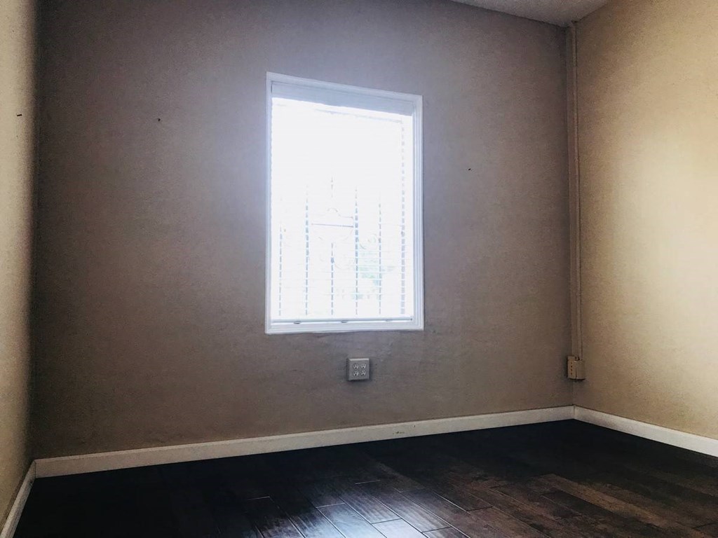 an empty room with a window and wooden floors
