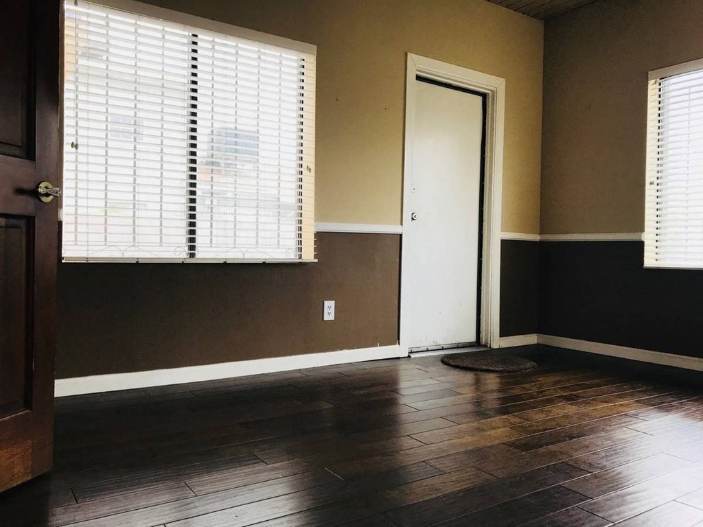 an empty room with wooden floors and a door and window