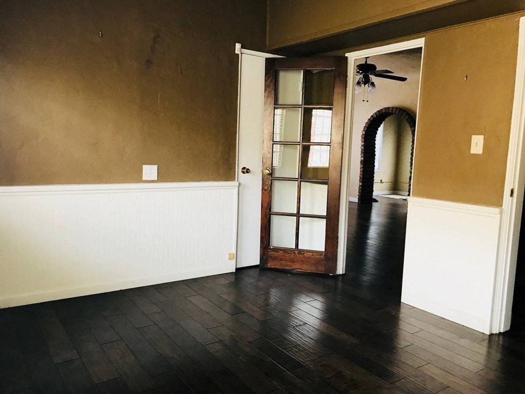 an empty living room with hard wood floors and a door