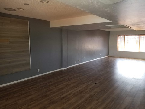 an empty living room with wood floors and grey walls