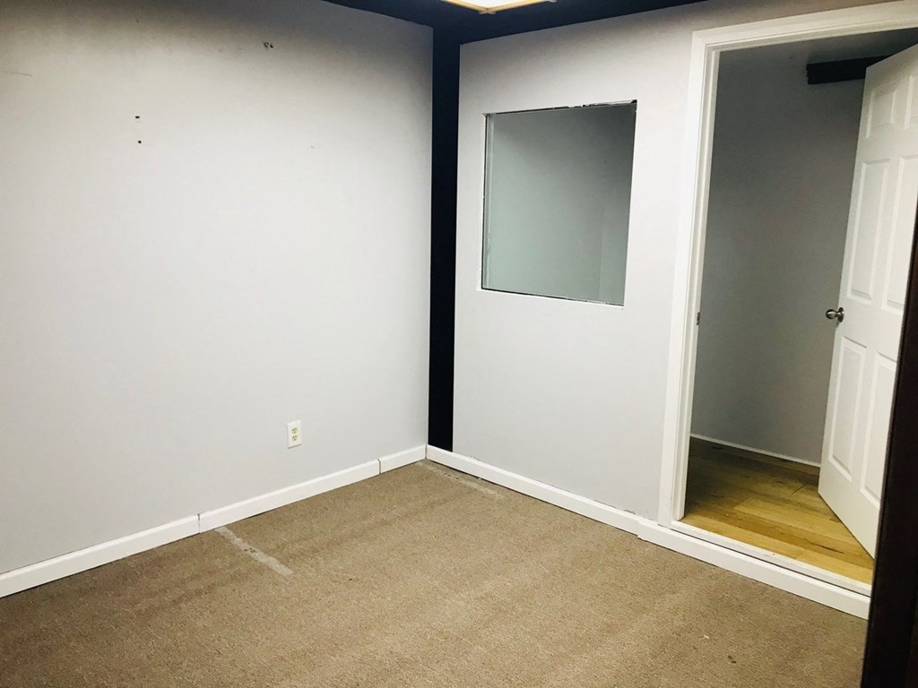 an empty room with a carpet and a door to a closet