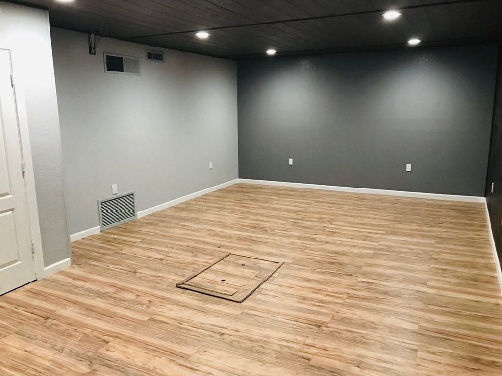 a living room with wood flooring and gray walls and a white door