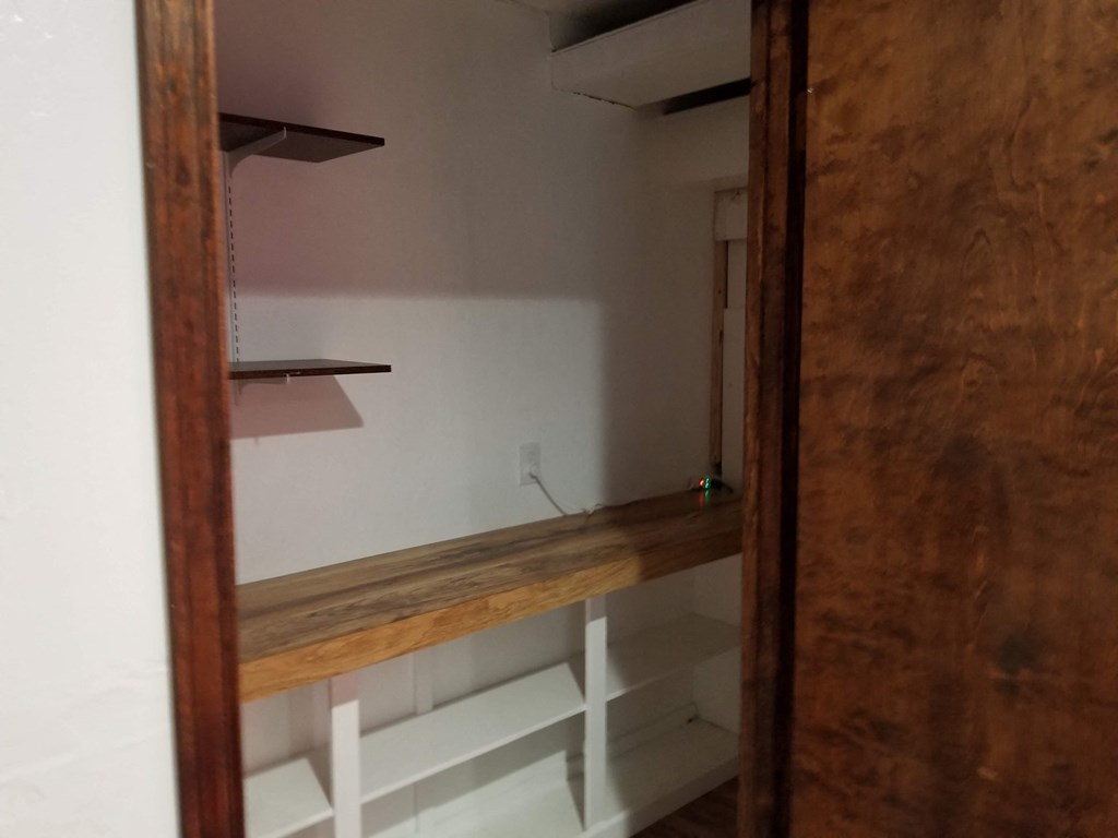 a room with a wooden shelf and a mirror