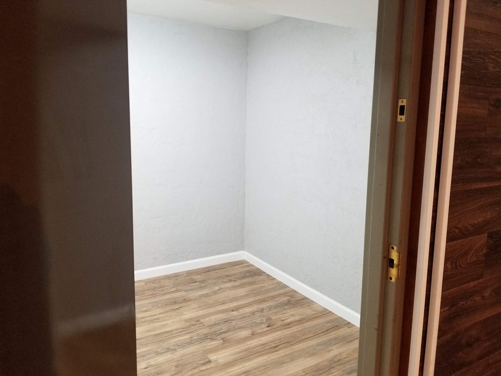 an empty room with wooden floors and a white wall