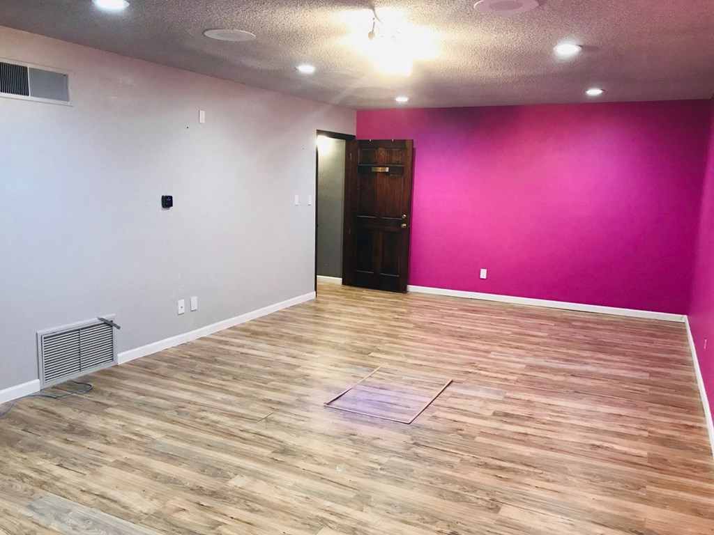 a white room with a pink wall and wooden floors