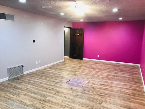 a white room with a pink wall and wooden floors