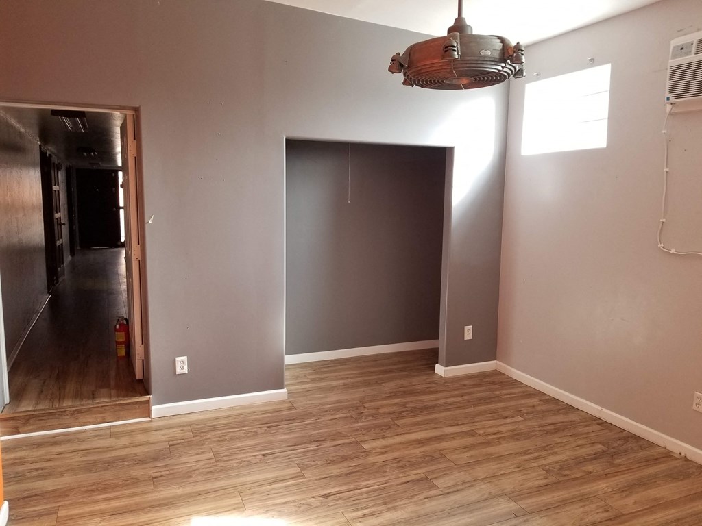 a living room with a hard wood floor and grey walls
