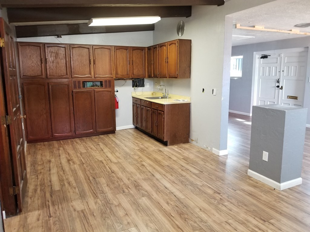 an empty kitchen with wood flooring and wooden cabinets
