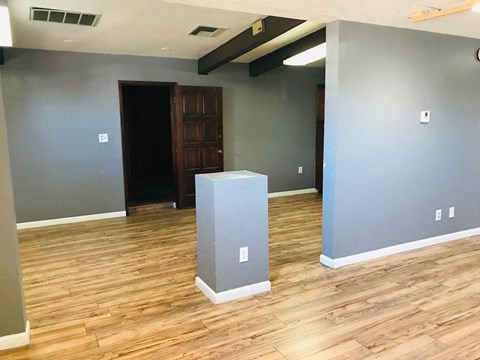 a living room with a wood floor and a gray pillar