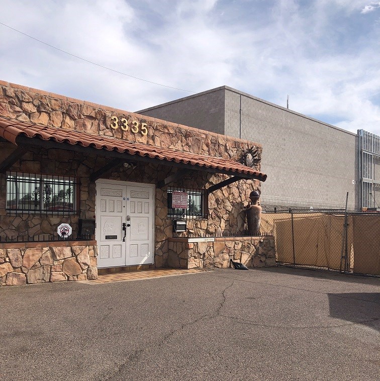 a stone building with a white door and a gate