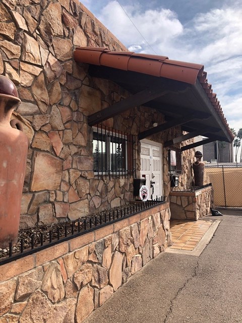 a stone building with a porch and a statue on the side