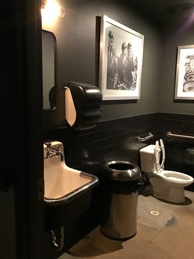 a bathroom with a toilet and a sink and a picture