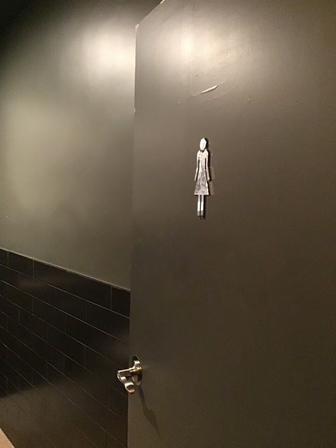 a bathroom stall with a statue of a woman on the wall