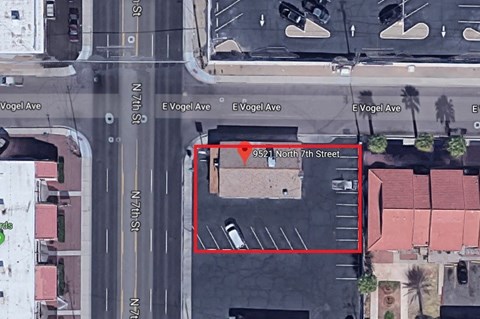 an aerial view of a parking lot with a car on the street