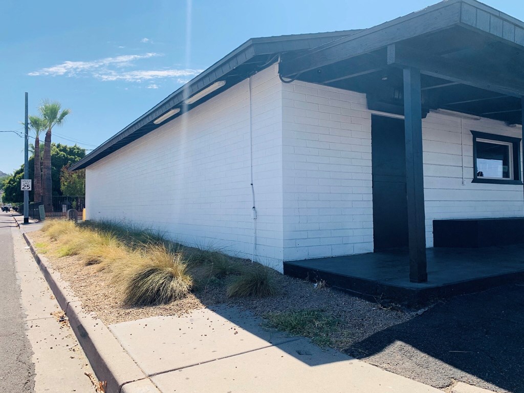 a white building with a black roof and a sidewalk