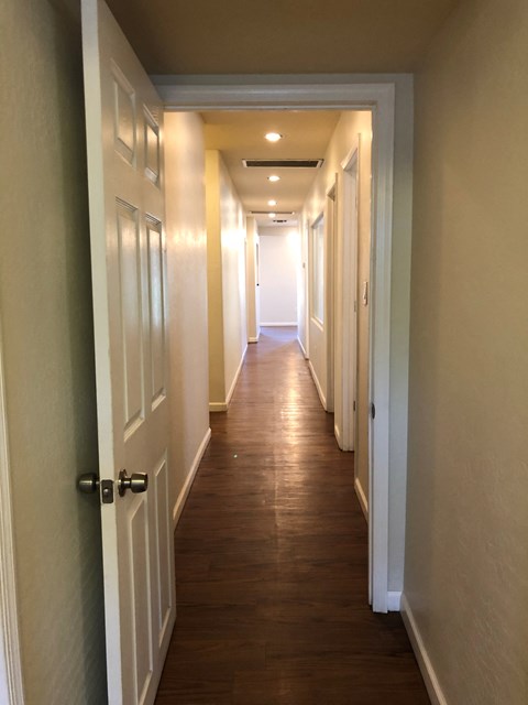 a long hallway with wooden floors and white doors