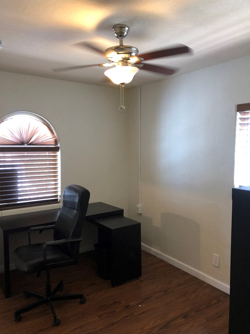 an office with a ceiling fan and a desk