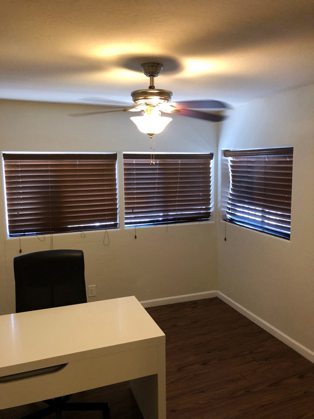 a small office with a desk and a ceiling fan