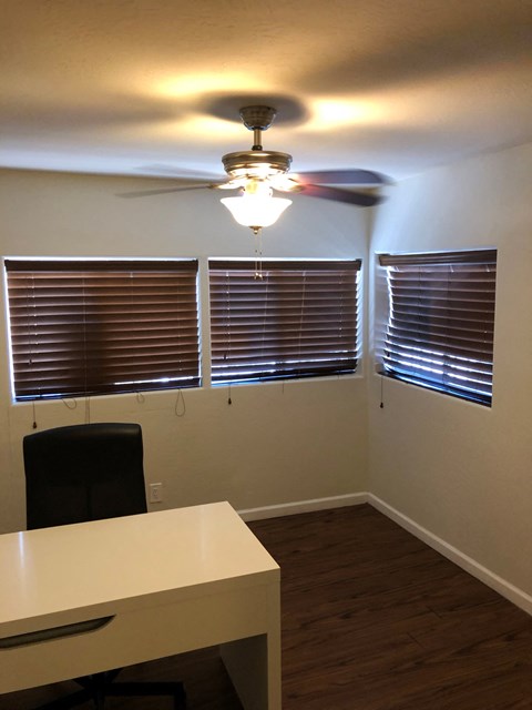 a small office with a desk and a ceiling fan