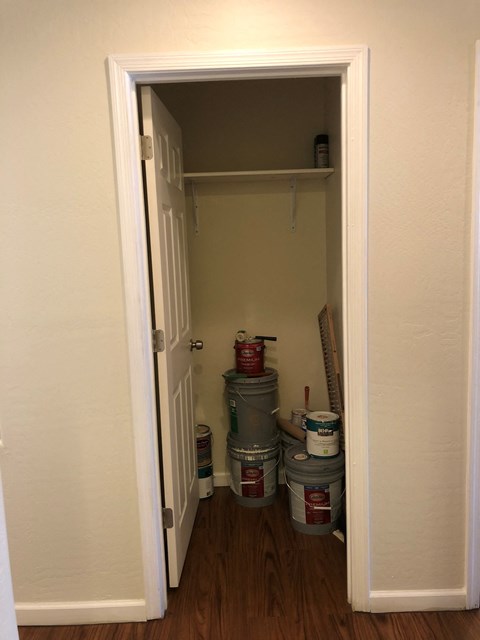 the pantry door is open to a small closet with paint buckets
