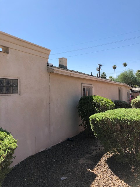 the side of a building with bushes and a driveway