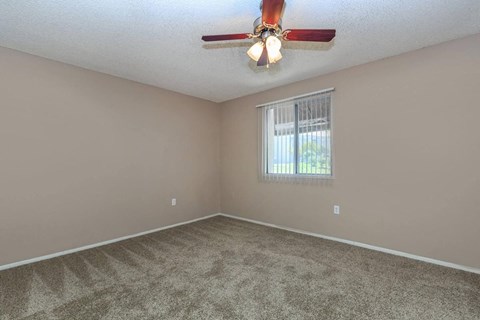 an empty living room with a ceiling fan and a window