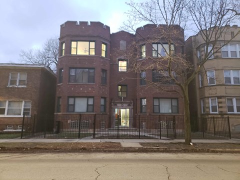 A large red brick building with a black fence in front.