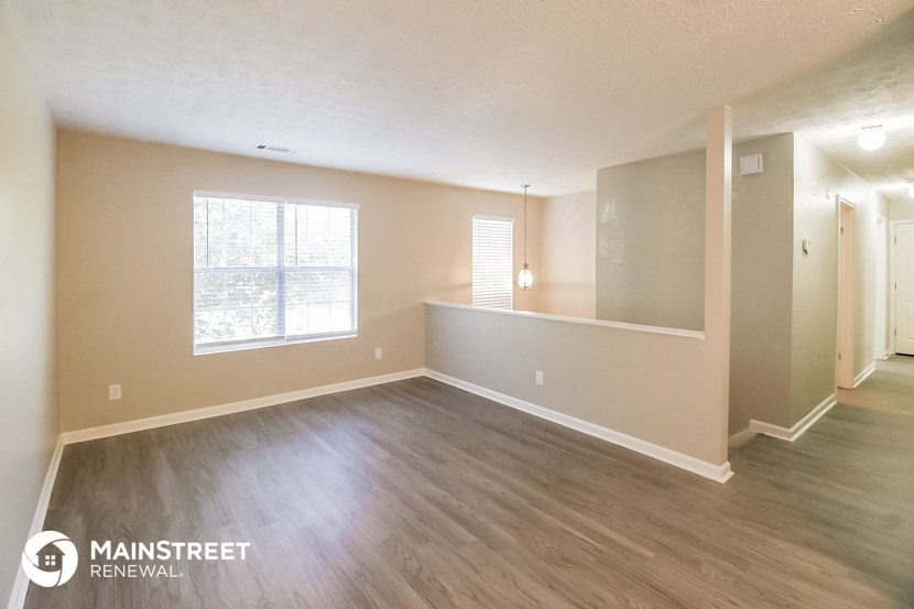 the spacious living room with hardwood flooring and a large window