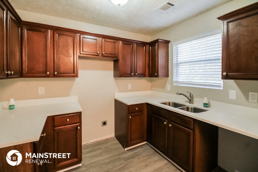 a kitchen with wooden cabinets and white counter tops and a sink