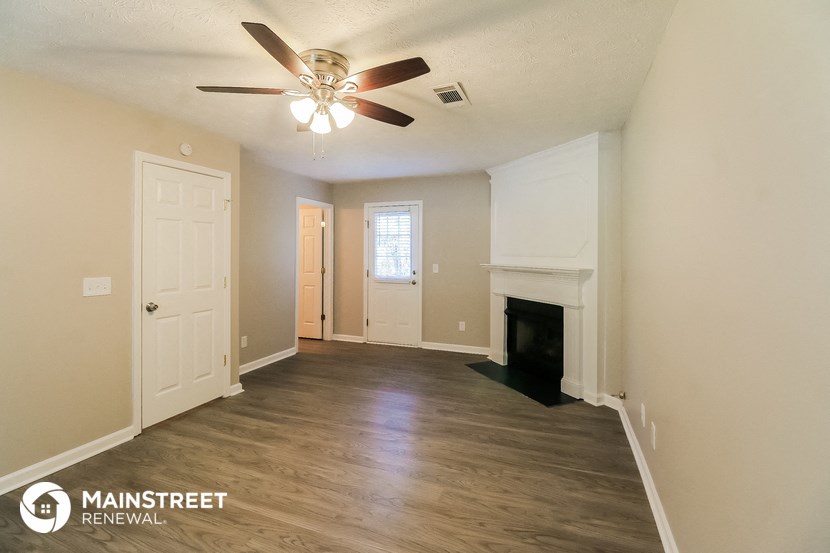 an empty living room with a ceiling fan and a fireplace
