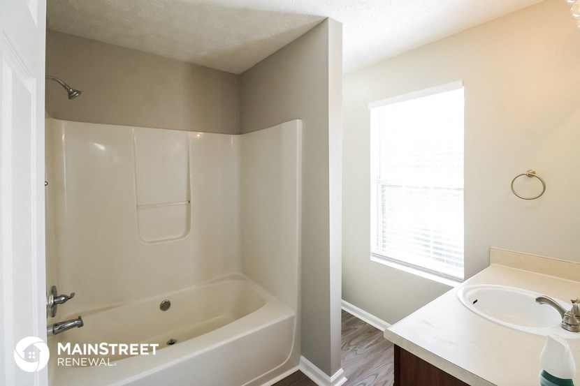 a bathroom with a tub and a sink and a window