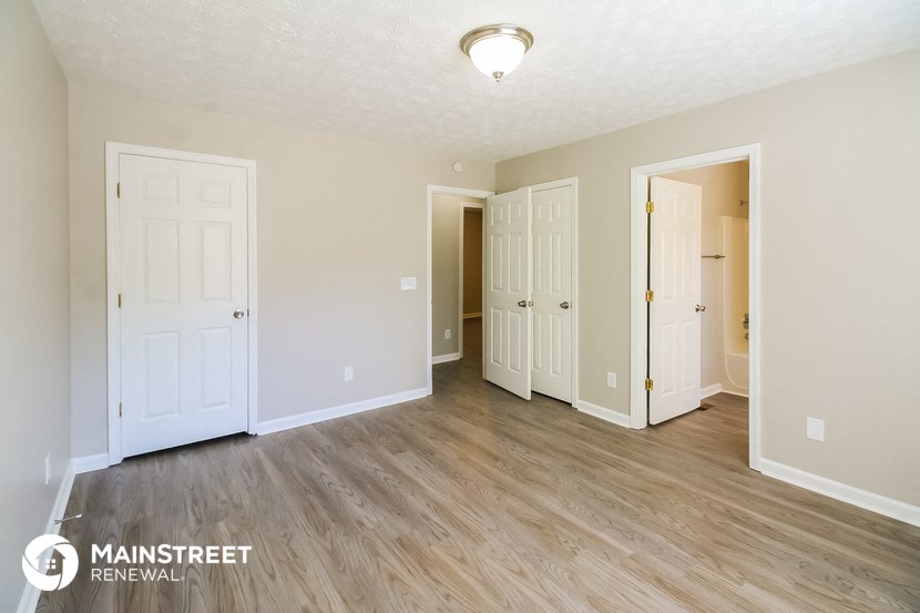 the living room of an apartment with wood flooring and white doors