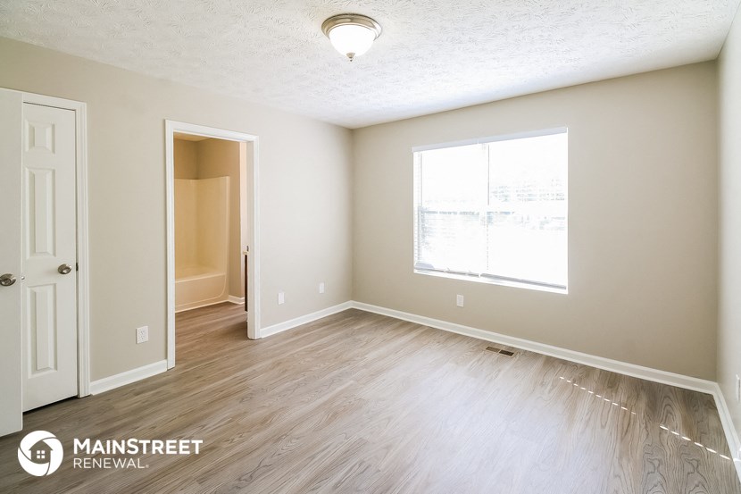 the spacious living room with wood flooring and a large window
